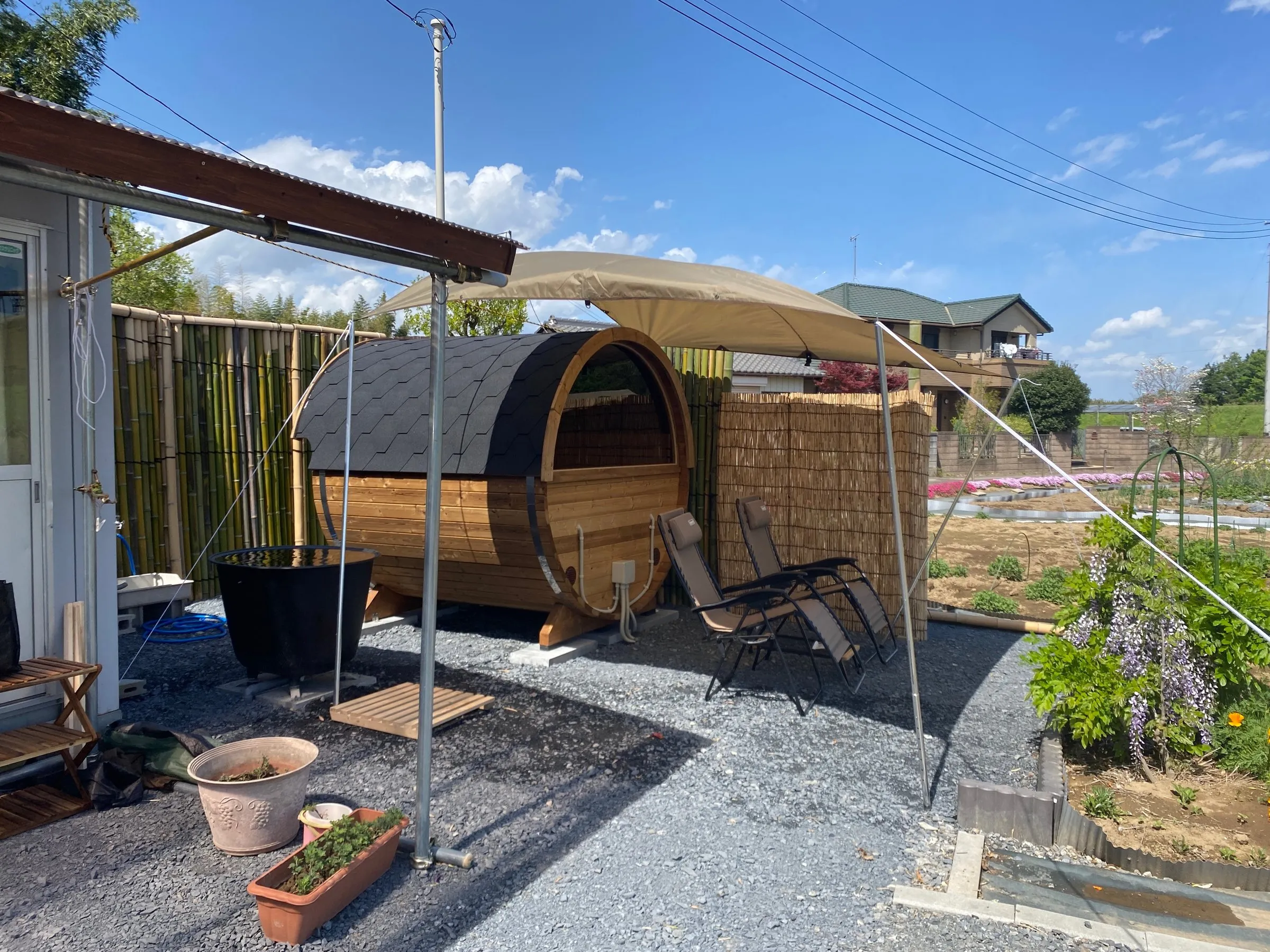 The tarp rigged over the infinity chairs beside the barrel — pitched here on a sunnier day