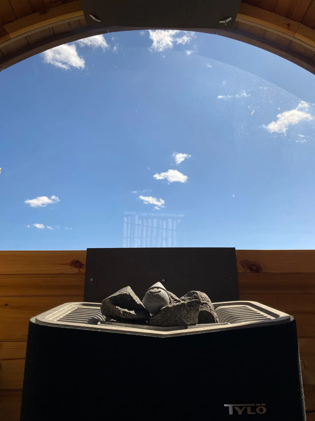 Sauna stones on the Tylö heater under the arch window, blue sky above